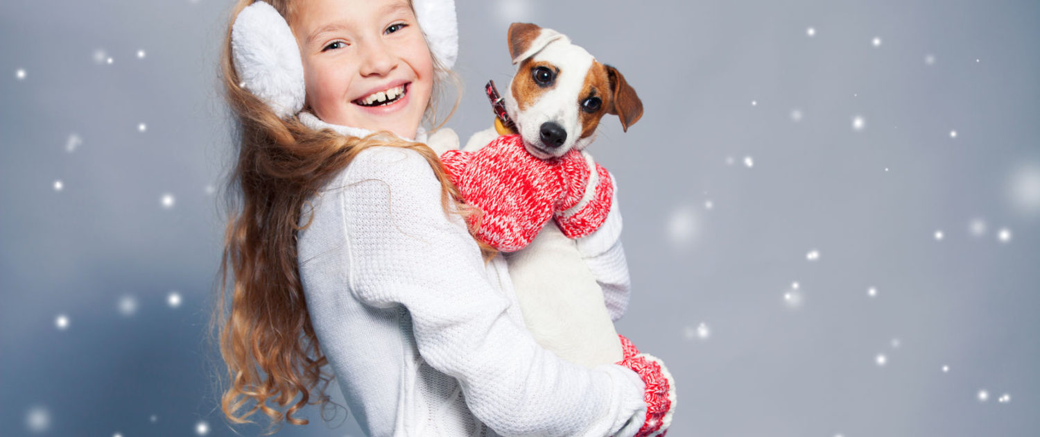 girl with dog in winter clothes. happy child. studio shot