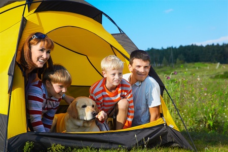  family outdoor portrait of smiling mother, two boys, young man and labrador looking happy outside of tent