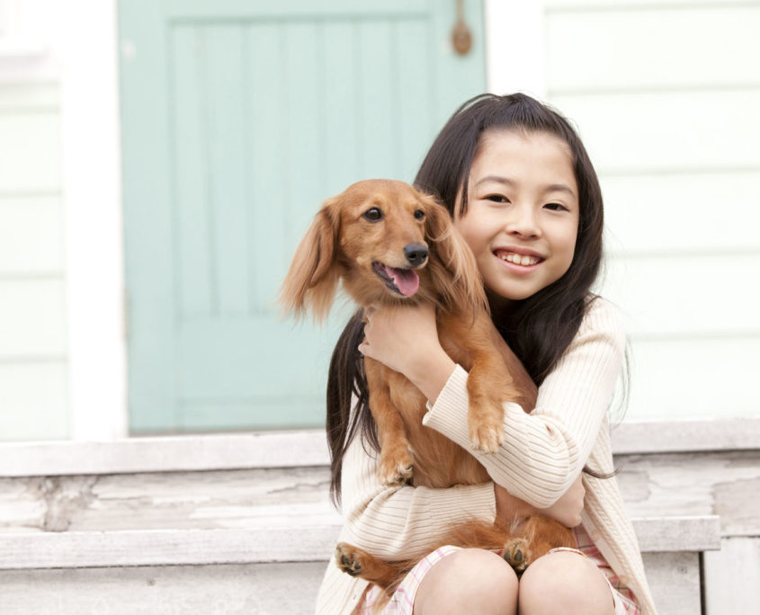 girl hugging a miniature dachshund